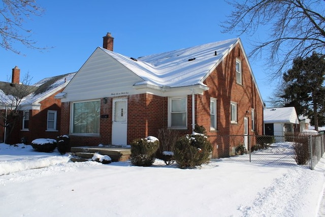 view of front of house featuring brick siding, a chimney, and fence