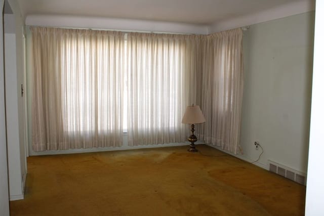 carpeted empty room featuring visible vents