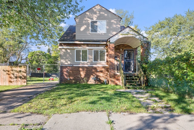 view of front facade featuring brick siding, fence, and a front lawn