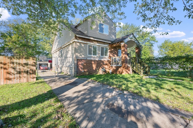 view of front of house with driveway, a gate, fence, a front lawn, and brick siding