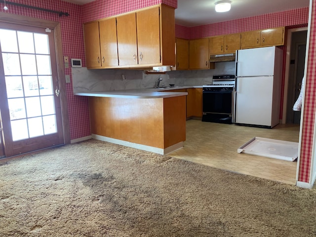 kitchen featuring freestanding refrigerator, light countertops, gas range, and wallpapered walls