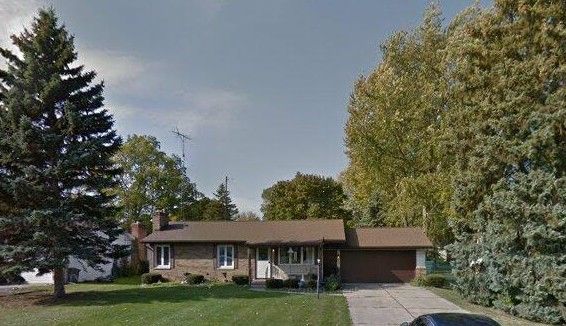 ranch-style home featuring a garage, a chimney, a front lawn, and concrete driveway