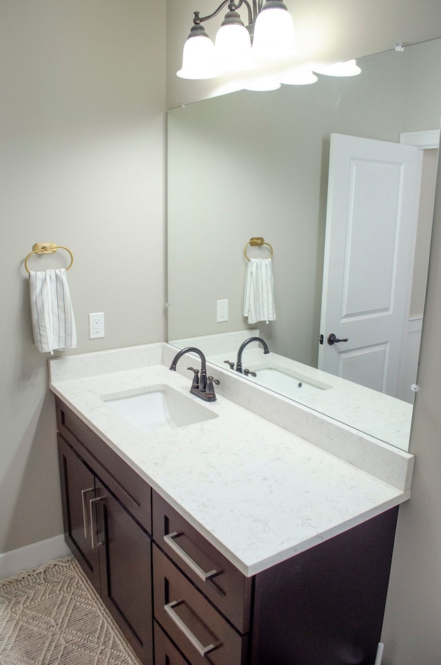 bathroom with baseboards, a chandelier, and vanity