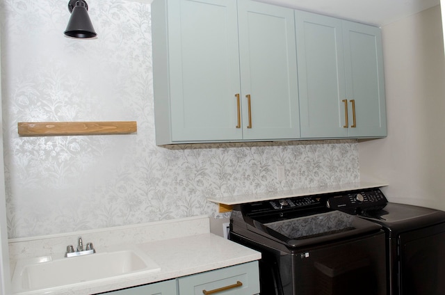 laundry room with a sink, wallpapered walls, washer and dryer, and cabinet space