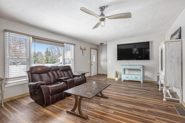 living area with a textured ceiling, dark wood-style flooring, visible vents, and baseboards