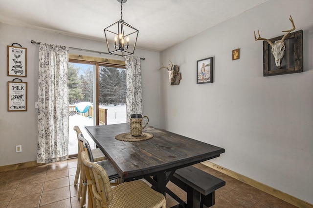 dining area with dark tile patterned floors, a chandelier, and baseboards