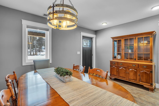 dining space featuring an inviting chandelier, light wood-style flooring, and visible vents