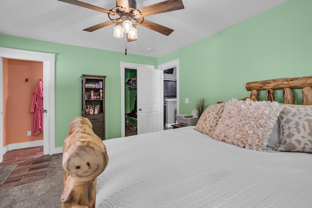 bedroom featuring dark wood-style flooring, a closet, a spacious closet, a ceiling fan, and baseboards