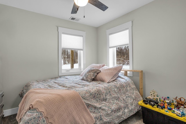 carpeted bedroom with ceiling fan, multiple windows, visible vents, and baseboards