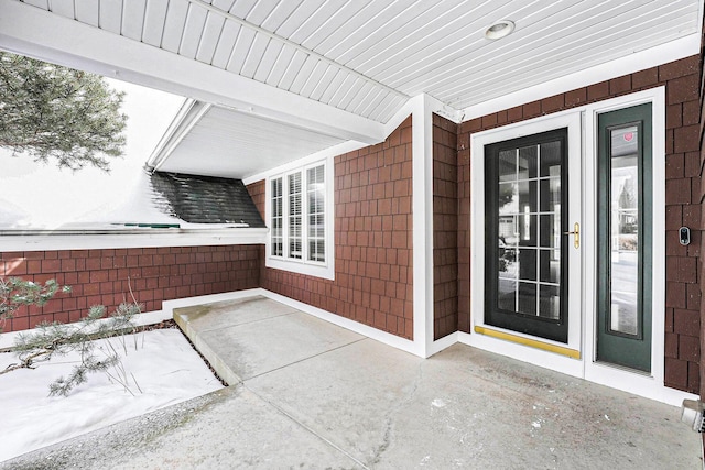 snow covered property entrance featuring a patio and fence