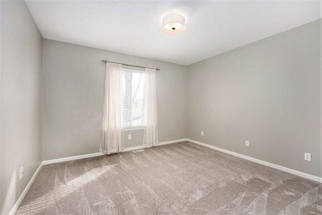 carpeted spare room featuring a textured ceiling, visible vents, and baseboards