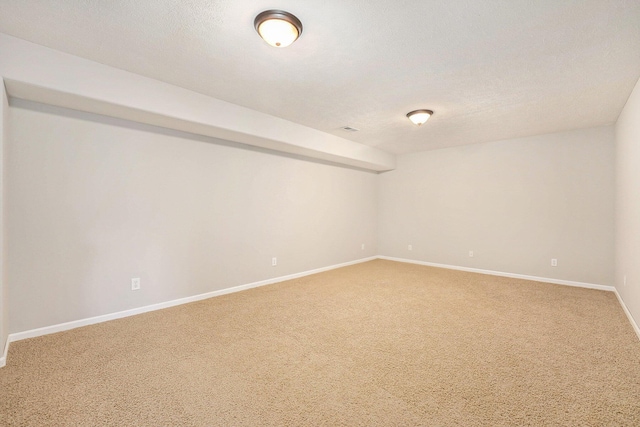 carpeted spare room featuring a textured ceiling and baseboards