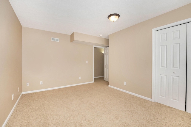 unfurnished bedroom featuring a closet, carpet, visible vents, and baseboards