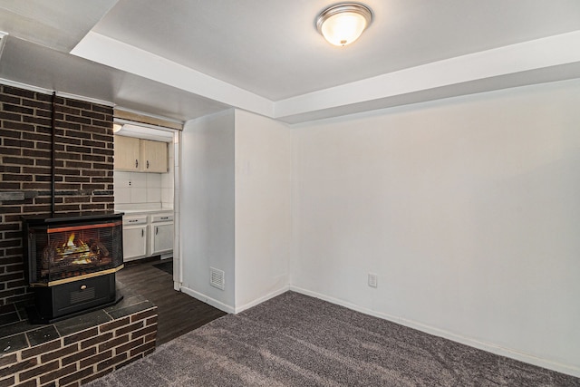 unfurnished living room with dark colored carpet, visible vents, and baseboards