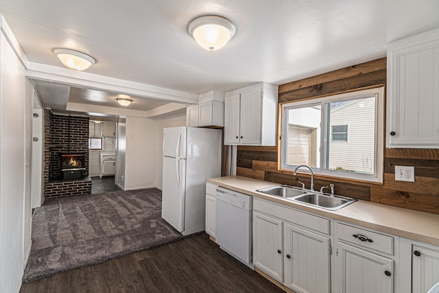 kitchen featuring white appliances, a brick fireplace, white cabinets, and a sink