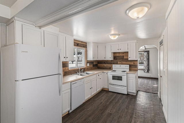 kitchen featuring white appliances, white cabinetry, arched walkways, and a sink