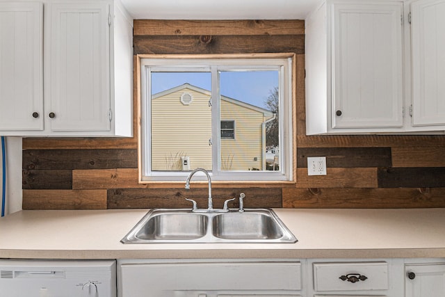 kitchen featuring light countertops, white cabinetry, a sink, and dishwashing machine