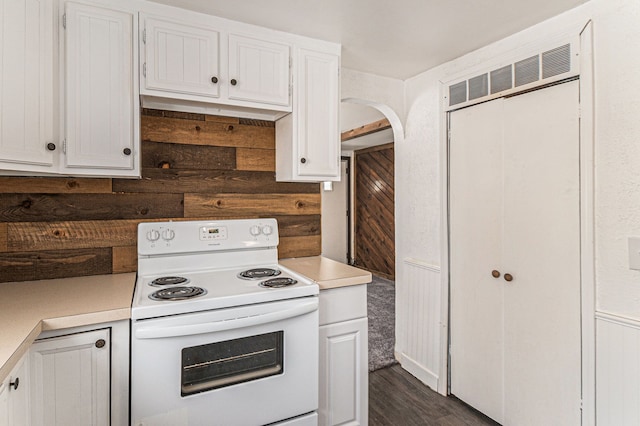 kitchen featuring wood walls, white range with electric stovetop, white cabinetry, and light countertops