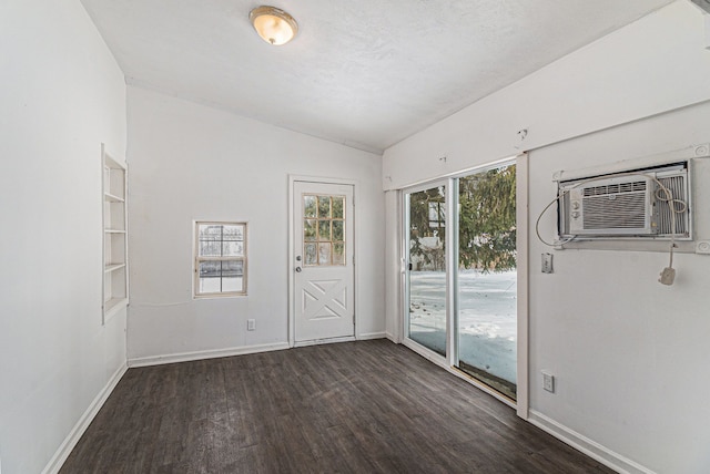 empty room with baseboards, dark wood-style flooring, plenty of natural light, and a wall mounted air conditioner