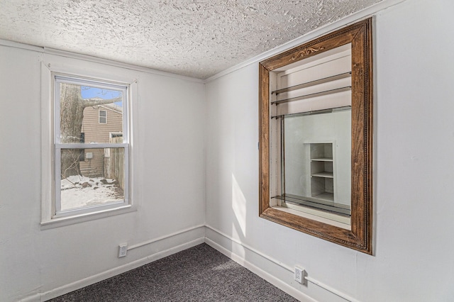 empty room with a textured ceiling, dark colored carpet, and baseboards