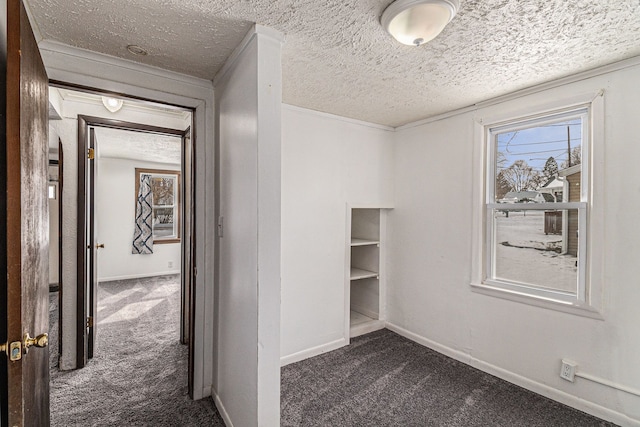 hall with dark carpet, a textured ceiling, and baseboards