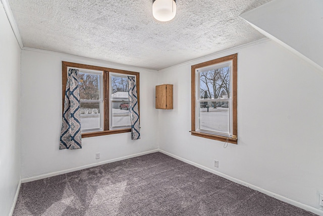 spare room with carpet floors, ornamental molding, a textured ceiling, and baseboards