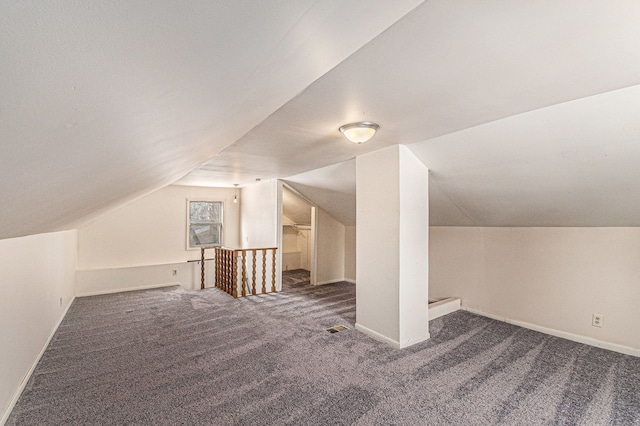 bonus room featuring lofted ceiling, carpet, visible vents, and baseboards