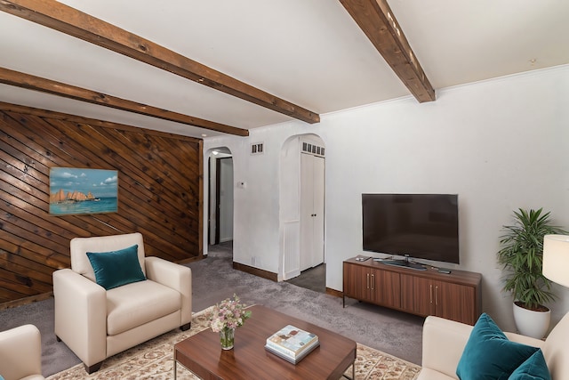 living area featuring arched walkways, wooden walls, carpet flooring, visible vents, and beamed ceiling