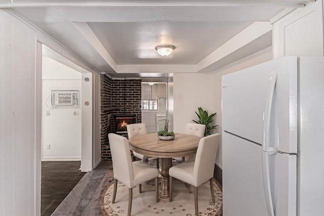 dining space featuring a wall mounted AC, a fireplace, wood finished floors, and baseboards