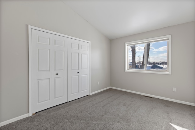 unfurnished bedroom with light colored carpet, vaulted ceiling, and baseboards