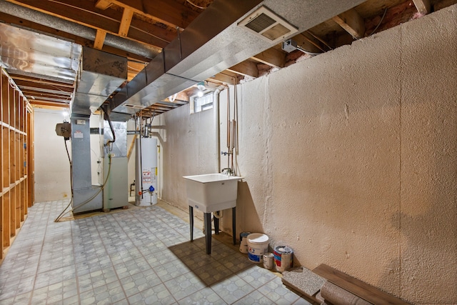 unfinished basement featuring visible vents, gas water heater, tile patterned floors, heating unit, and a sink