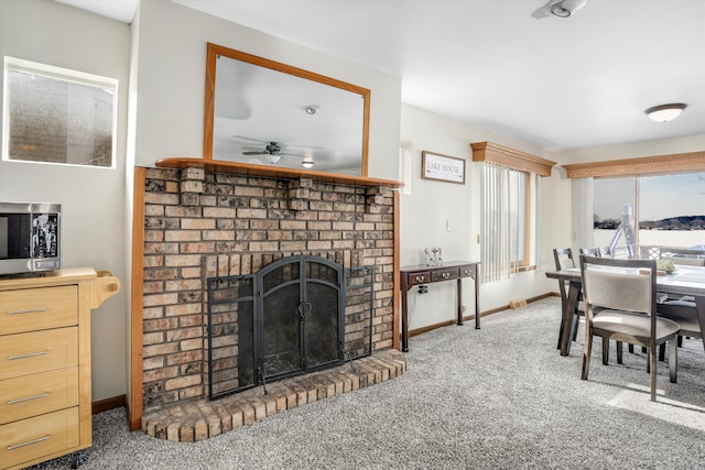 8860 Rushside Dr, Pinckney, MI 48169 - carpeted dining area featuring ceiling fan, a brick fireplace, and baseboards