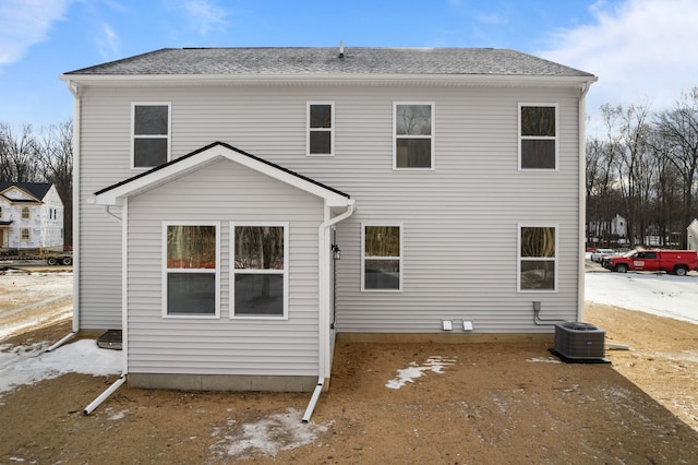 rear view of property with a shingled roof and central AC unit