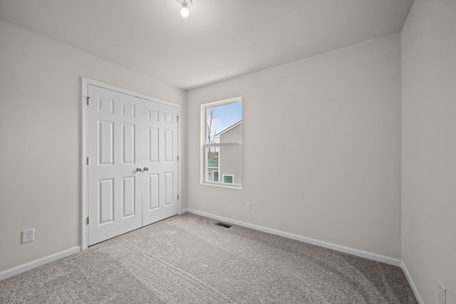 unfurnished bedroom featuring carpet, a closet, visible vents, and baseboards