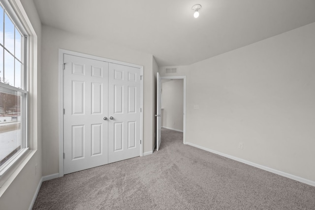 unfurnished bedroom featuring a closet, visible vents, baseboards, and carpet flooring