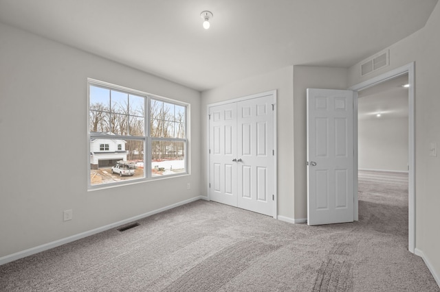 unfurnished bedroom with light colored carpet, a closet, visible vents, and baseboards