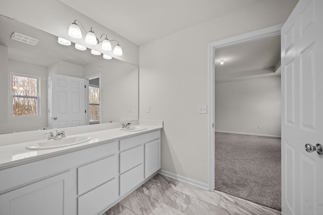 bathroom featuring visible vents, a sink, baseboards, and double vanity