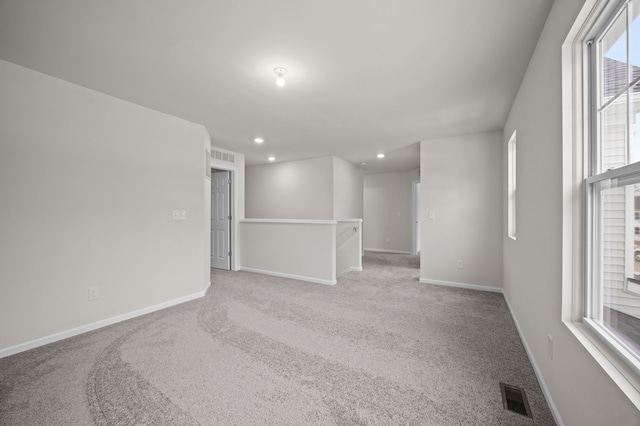 empty room with baseboards, visible vents, and light colored carpet