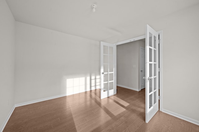 spare room with french doors, wood finished floors, and baseboards