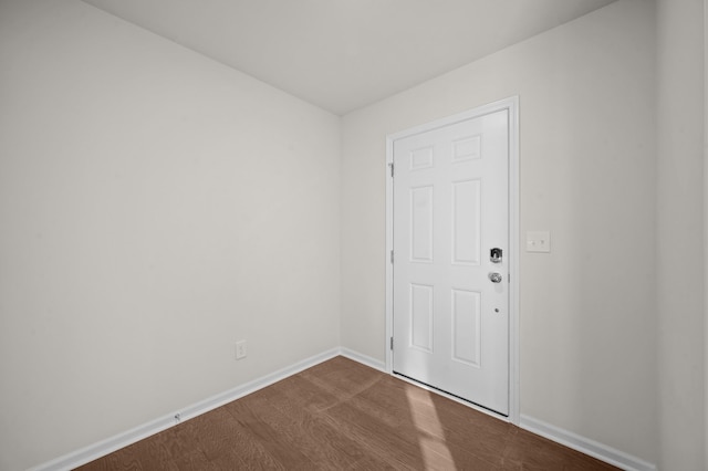 spare room featuring baseboards and wood finished floors