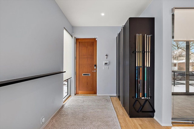 hall featuring light wood finished floors, recessed lighting, and baseboards