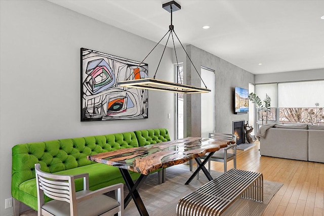 dining area featuring a warm lit fireplace and light wood finished floors