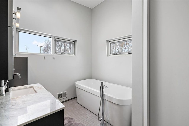 bathroom featuring a soaking tub, visible vents, and vanity