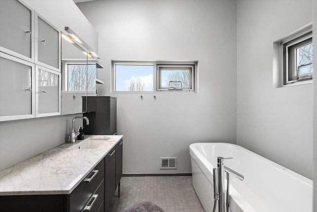 bathroom featuring a soaking tub, baseboards, visible vents, and vanity