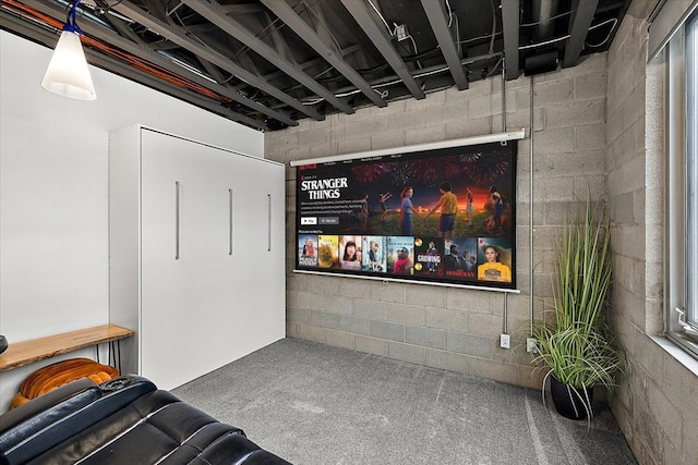 carpeted home theater room with concrete block wall