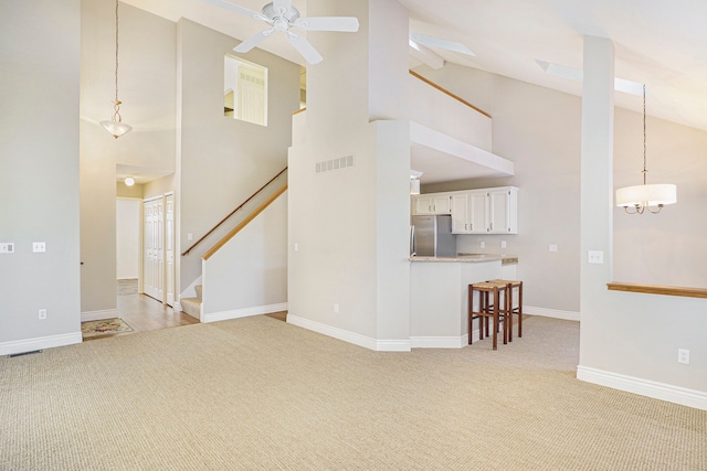 unfurnished living room with high vaulted ceiling, stairs, visible vents, and light colored carpet