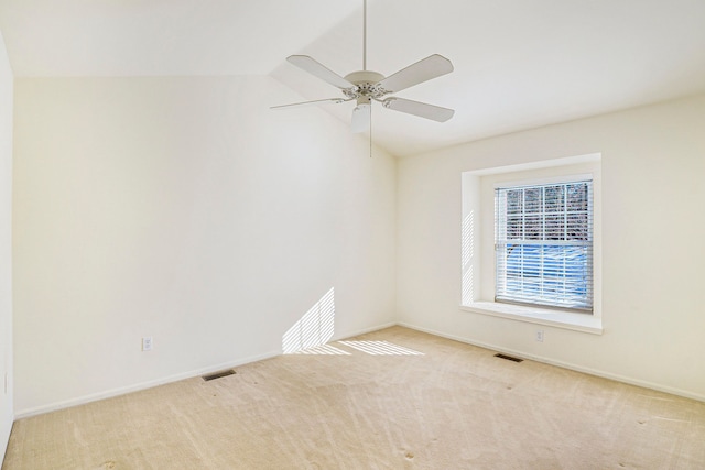 spare room with visible vents, vaulted ceiling, and light colored carpet