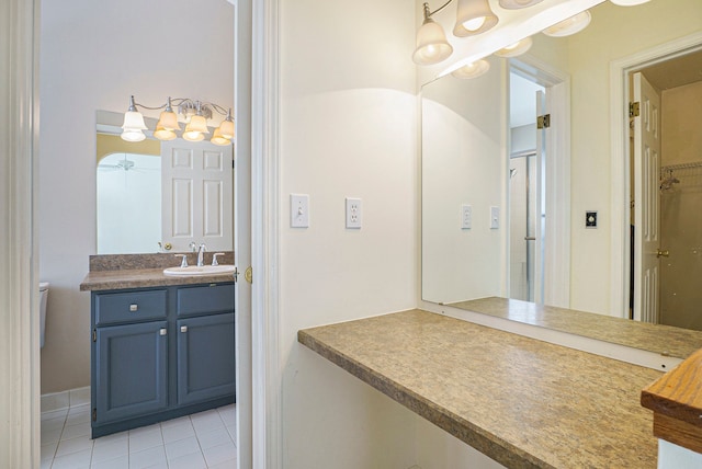 bathroom with a spacious closet, vanity, and tile patterned floors