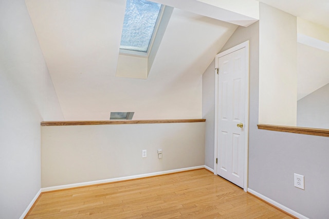 spare room featuring a skylight, baseboards, and wood finished floors