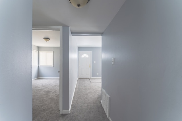 hallway featuring carpet, visible vents, and baseboards